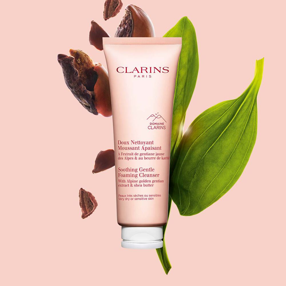 Packshot of the foaming cleanser light pink tube next to golden gentian and shea nuts on a light pink background