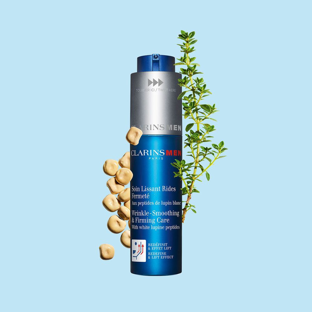 Packshot of the men's anti-ageing concentrate by Clarins next to white lupines on a light blue background to emphasize its key ingredient.