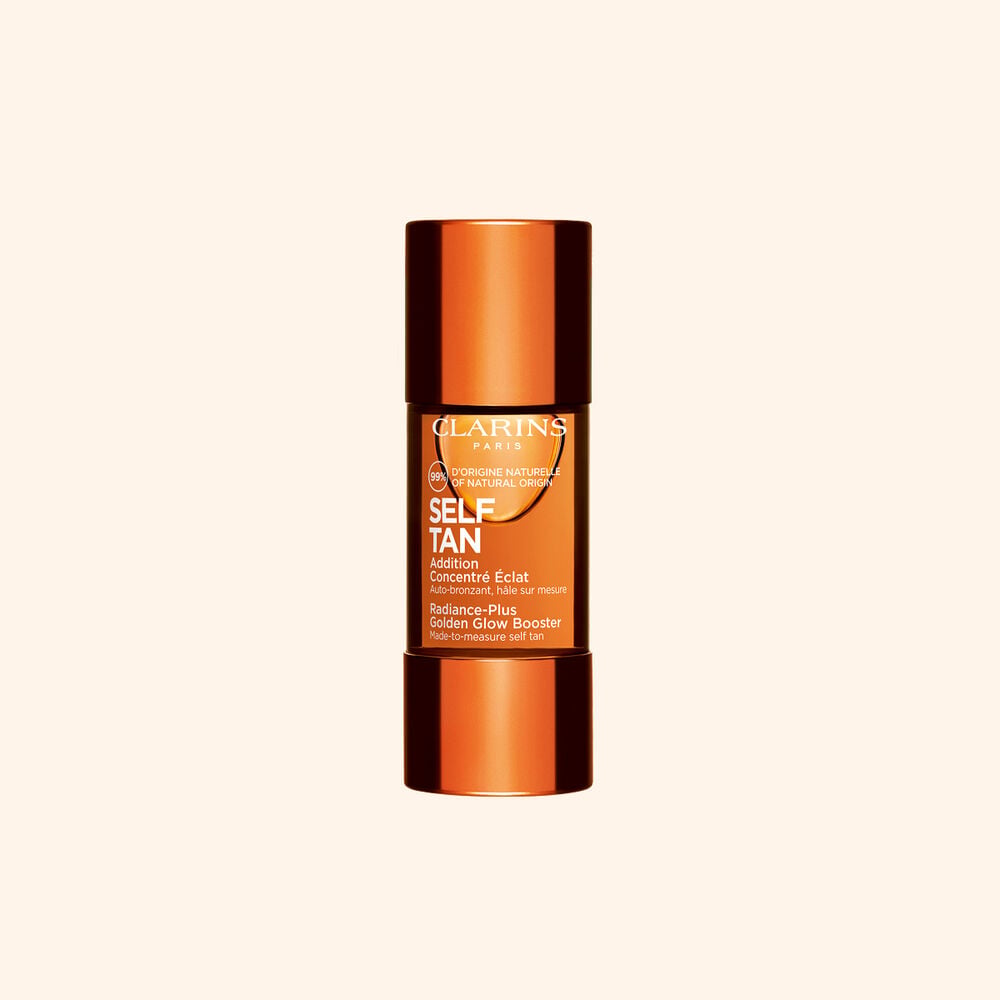 Clarins self tanning glow booster bottle displayed on a beige backdrop for a sun kissed radiant skin routine.