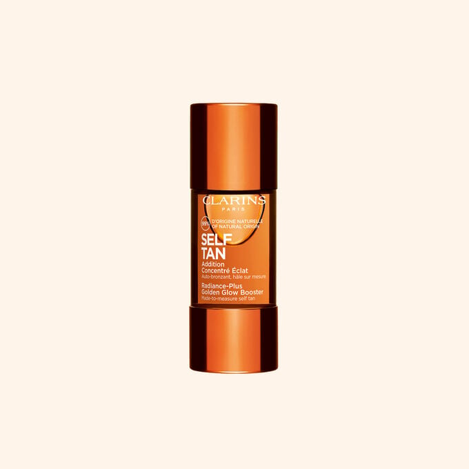 Clarins self tanning glow booster bottle displayed on a beige backdrop for a sun kissed radiant skin routine.