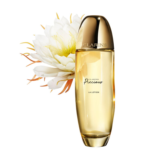 Packshot of Clarins Precious Treatment Essence close to a Moonlight flower on a dark background.