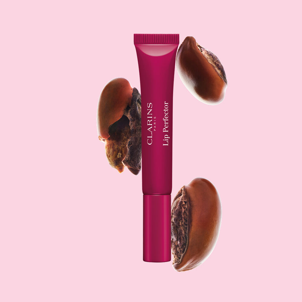 Plumping lip perfector tube shown with raw shea seeds to highlight the intense lip care formula for deep nourishment effect