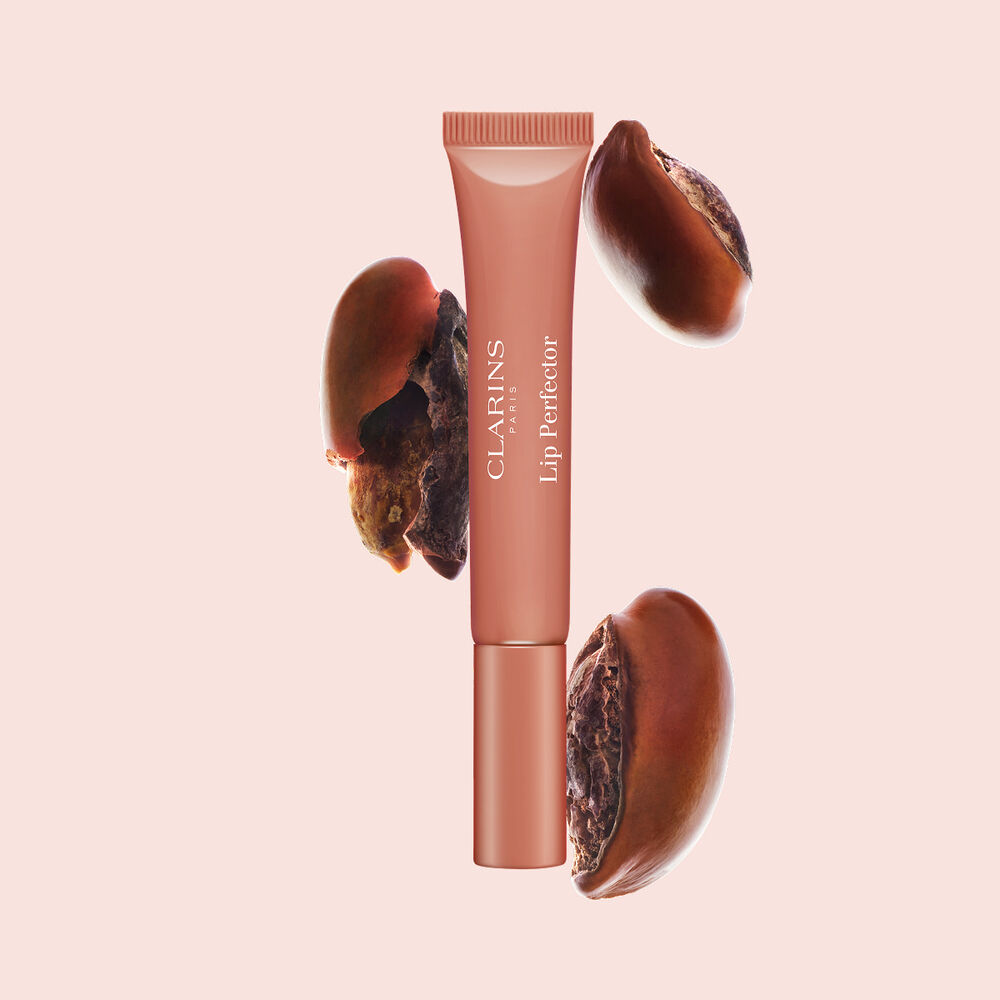 Plumping lip perfector tube shown with raw shea seeds to highlight the intense lip care formula for deep nourishment effect