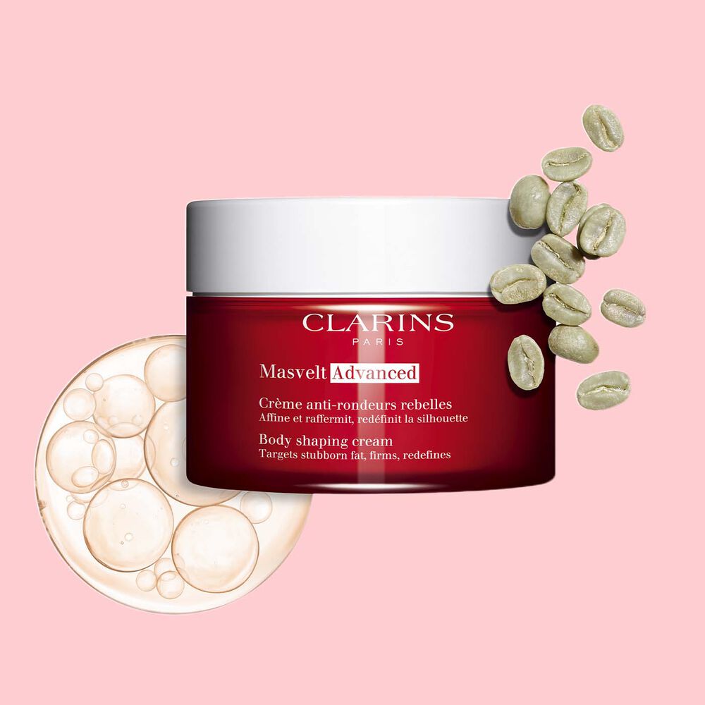 Packshot of Clarins Masvelt Advanced Body Shaping Cream close to coffee beans on a pale pink background.