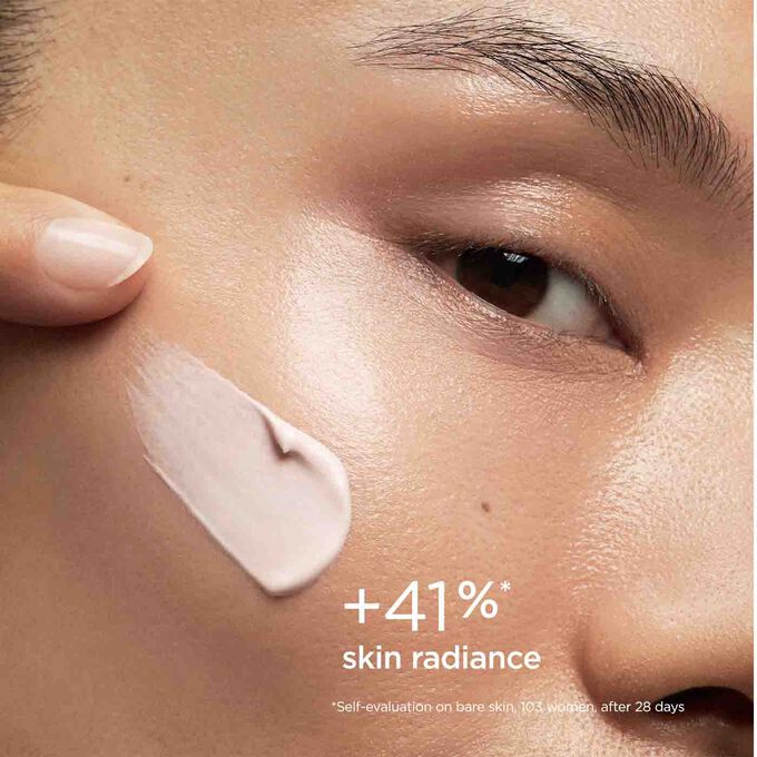 Woman with closed eyes, wearing SOS Primer Pink by Clarins on her face to illustrate that it reduces signs of fatigue by 20%.