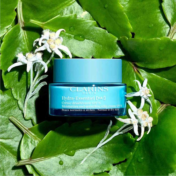 Packshot of Clarins Hydra-Essentiel SPF15 among leaves and edelweiss flowers with text emphasising its recyclable packaging.