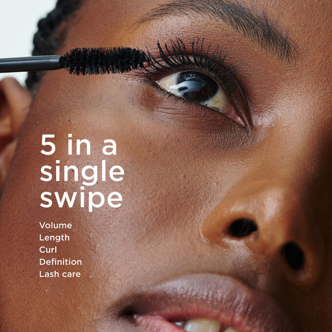 Focus on a woman applying Clarins Mascara, illustrating its 5-in-1 action: volume, length, curl, definition, and lash care in one swipe.