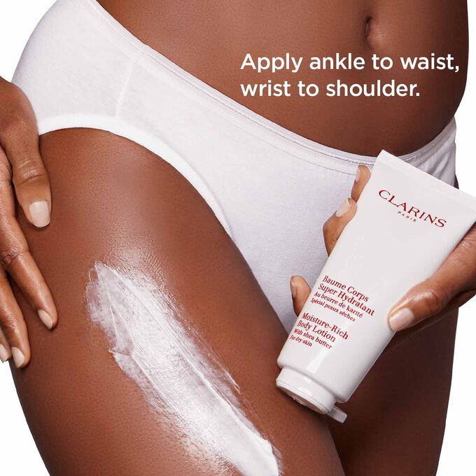 Clarins Moisture-Rich Body Lotion among orange tree leaves and shea nuts to illustrate the natural origin of the ingredients.