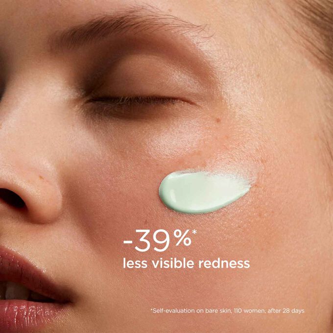 Woman with closed eyes wearing SOS Primer Green by Clarins on her face to illustrate that it reduces redness by 27%.
