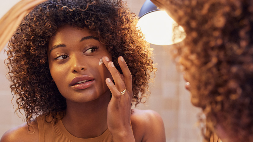 Woman looking at herself in the mirror, searching for the right anti-wrinkle cream to suit her skin&rsquo;s needs."